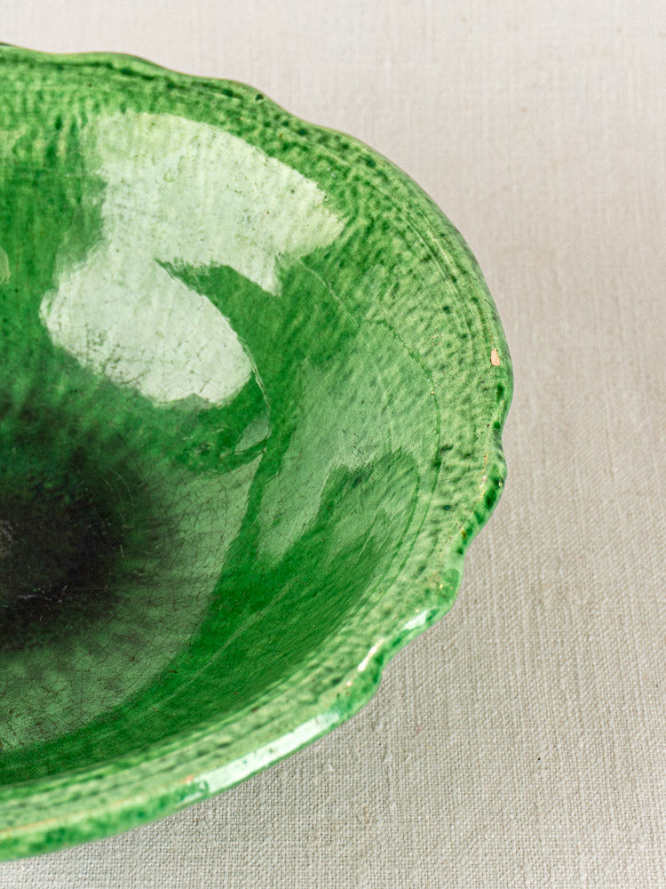 French Vallauris bowl by Foucard-Jourdan with scalloped rim and glossy green glaze on textured fabric.