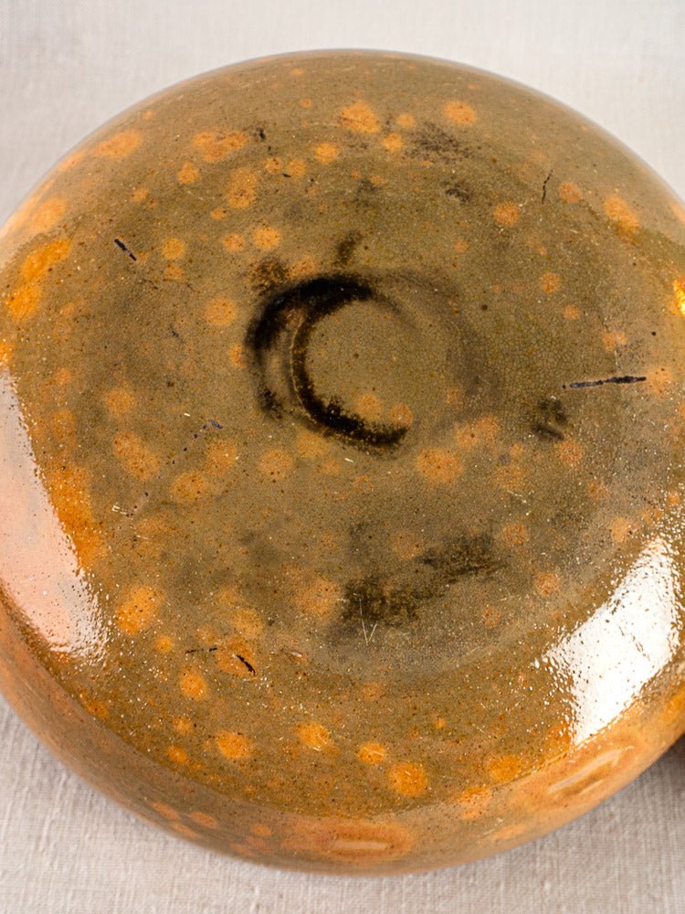 Close-up of antique Vallauris Jaspé Poêlon base with mottled brown, tan, and orange glazed ceramic.