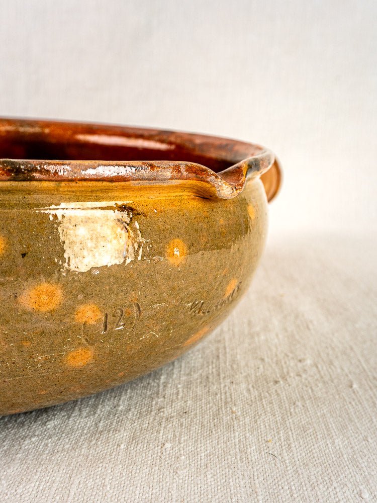 Vallauris Jaspé Poêlon antique French terracotta pan with earthy hues and worn ceramic details on light textured fabric.