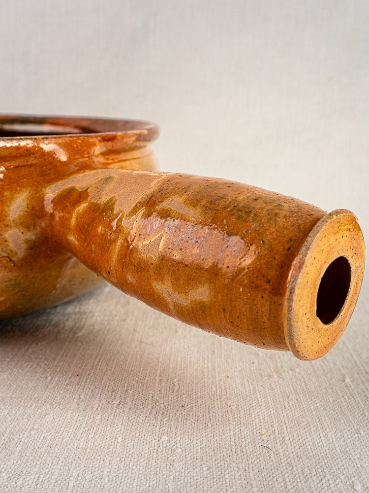 Vallauris Jaspé antique French terracotta poêlon with wide hollow handle and glossy brown glaze.