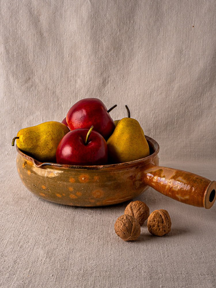 Antique French Vallauris Jaspé terracotta cooking pan with apples, pears, and walnuts on neutral cloth.