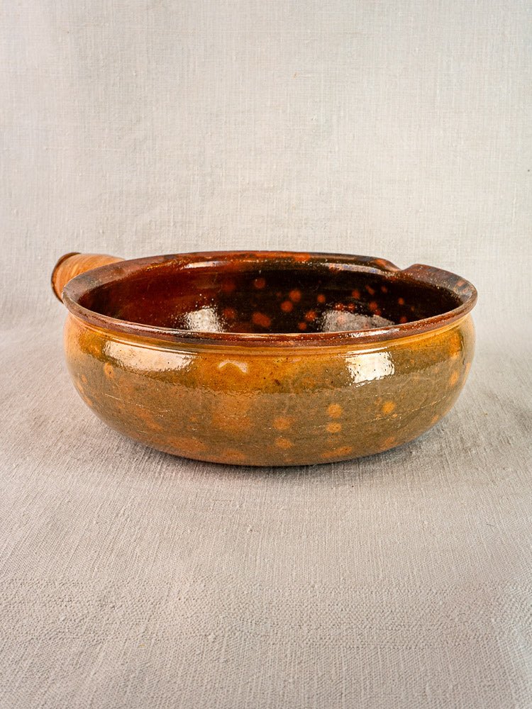 Antique French Vallauris Jaspé terracotta cooking pan with brown glaze and side handle on gray surface.