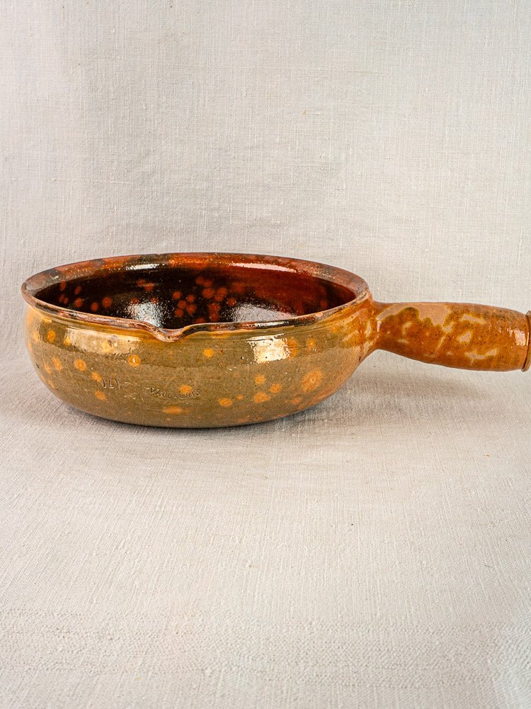Antique French Vallauris Jaspé terracotta poêlon with brown speckled glaze on a light surface.