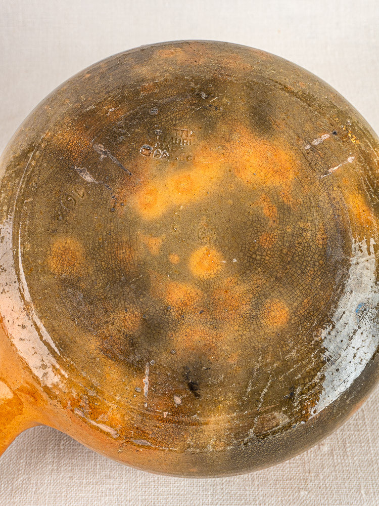 Dish base with black scorch marks, scratches, and heavy wear on neutral fabric background.