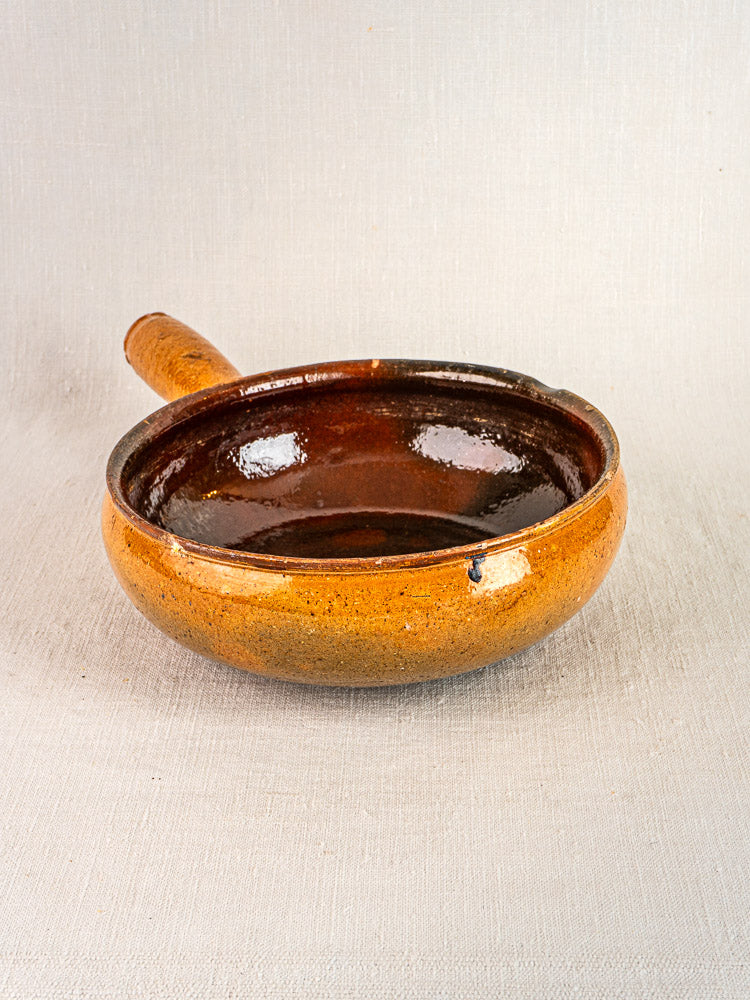 Antique Vallauris terracotta bowl with glazed interior and side handle, brown and orange tones.
