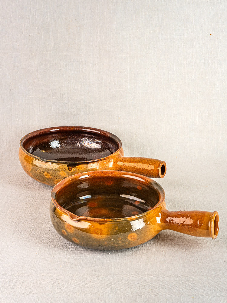 Pair of antique French Vallauris terracotta poêlons with side handles, warm brown-orange glaze.