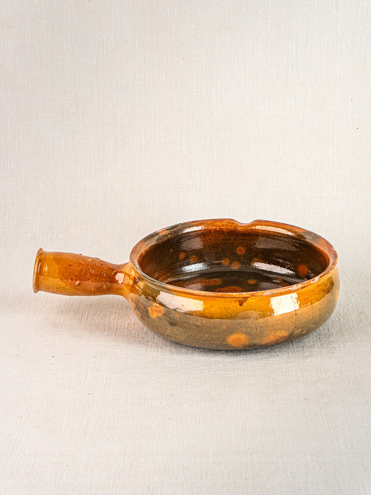 Round brown glazed ceramic Vallauris poêlon with single handle, rustic finish, textured surface.