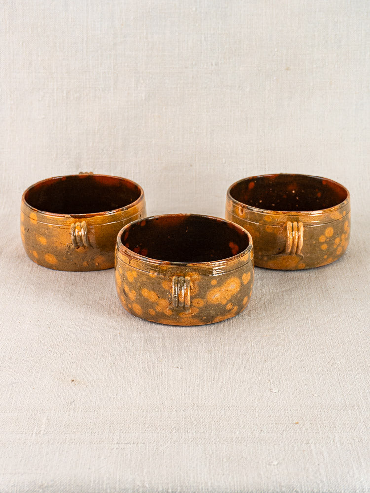 Set of three vintage French Vallauris earthenware bowls with brown glaze, yellow spots, and ridged exteriors.