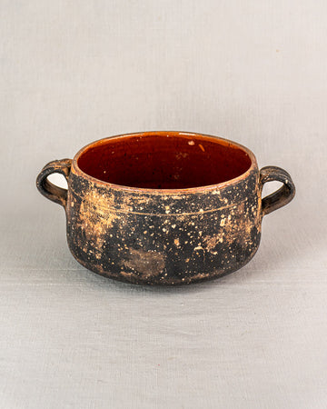Early 20th-century French Vallauris terracotta pot with side handles, speckled glaze, on light gray background.