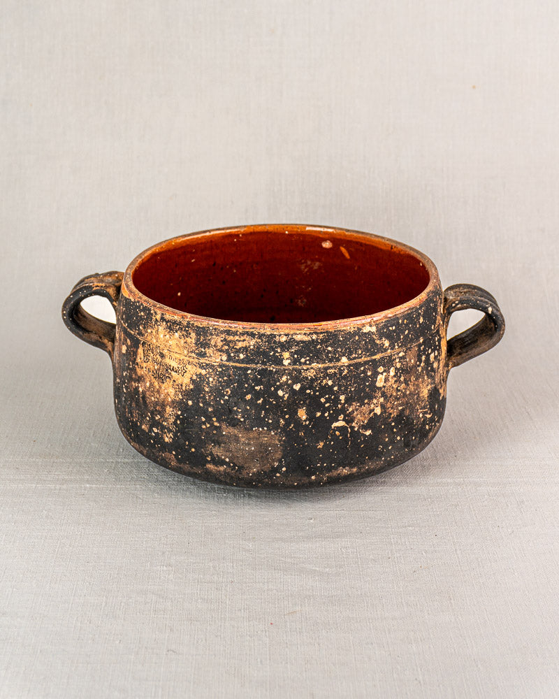 Early 20th-century French Vallauris terracotta pot with side handles, speckled glaze, on light gray background.