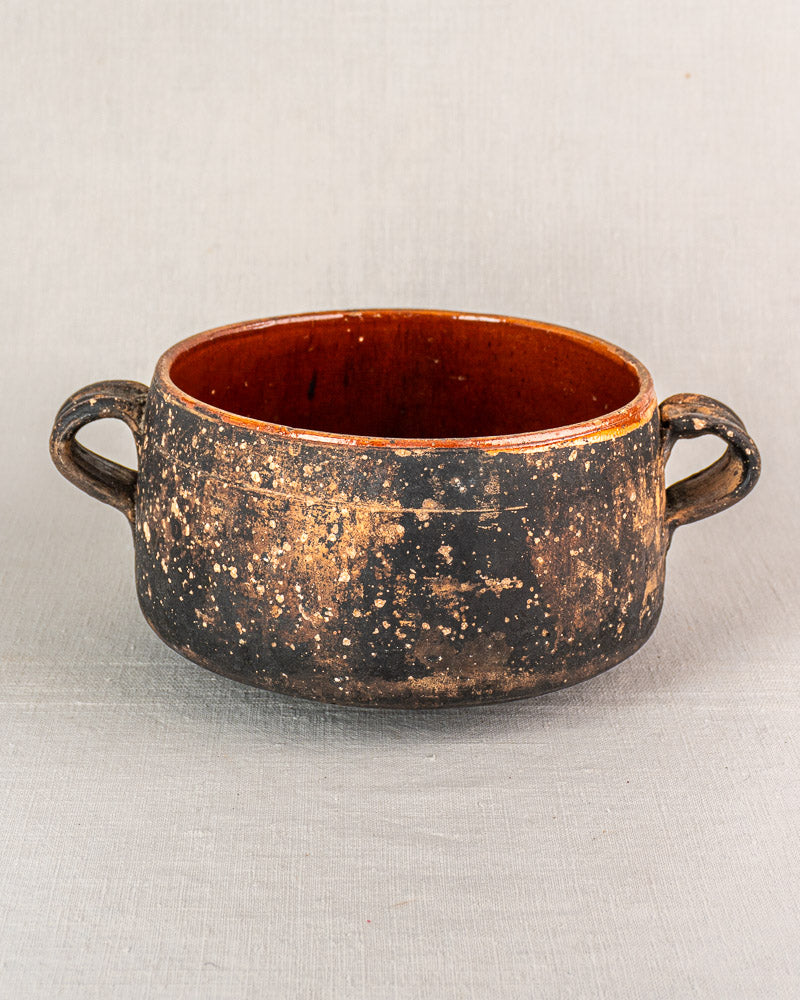 Early 20th century French Vallauris glazed terracotta cooking pot, rustic double handles, on a light gray background.