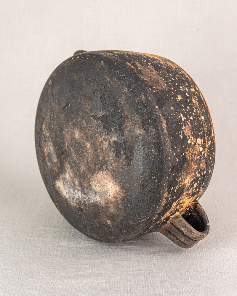Vintage French Vallauris glazed terracotta cooking pot upside down, two handles, heavy blackening and discoloration visible.