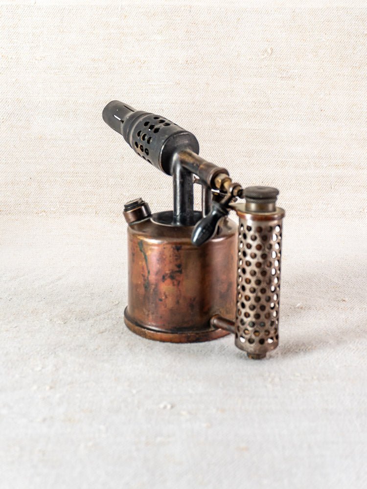 Antique French brass blowtorch by Vesta F.J. Paris, circa 1920, on a textured background.