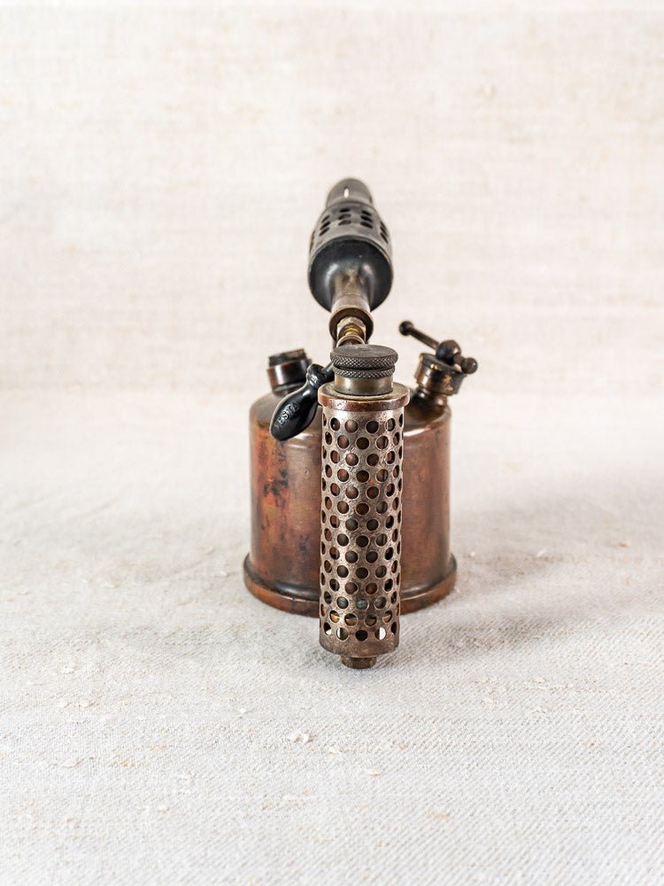 Vintage French Vesta F.J. Paris blowtorch, circa 1920, upright with perforated cylindrical handle on light surface.