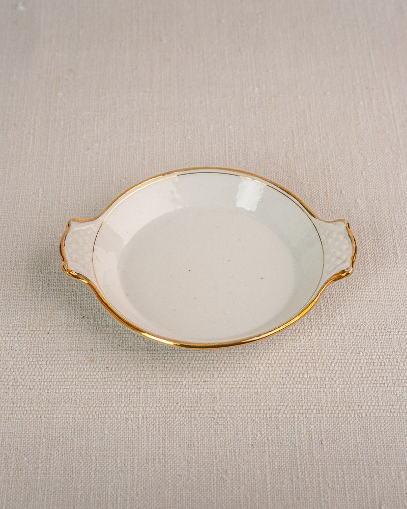 Set of three 19th-century French Vieux Paris porcelain serving dishes with gold rims on cream fabric.