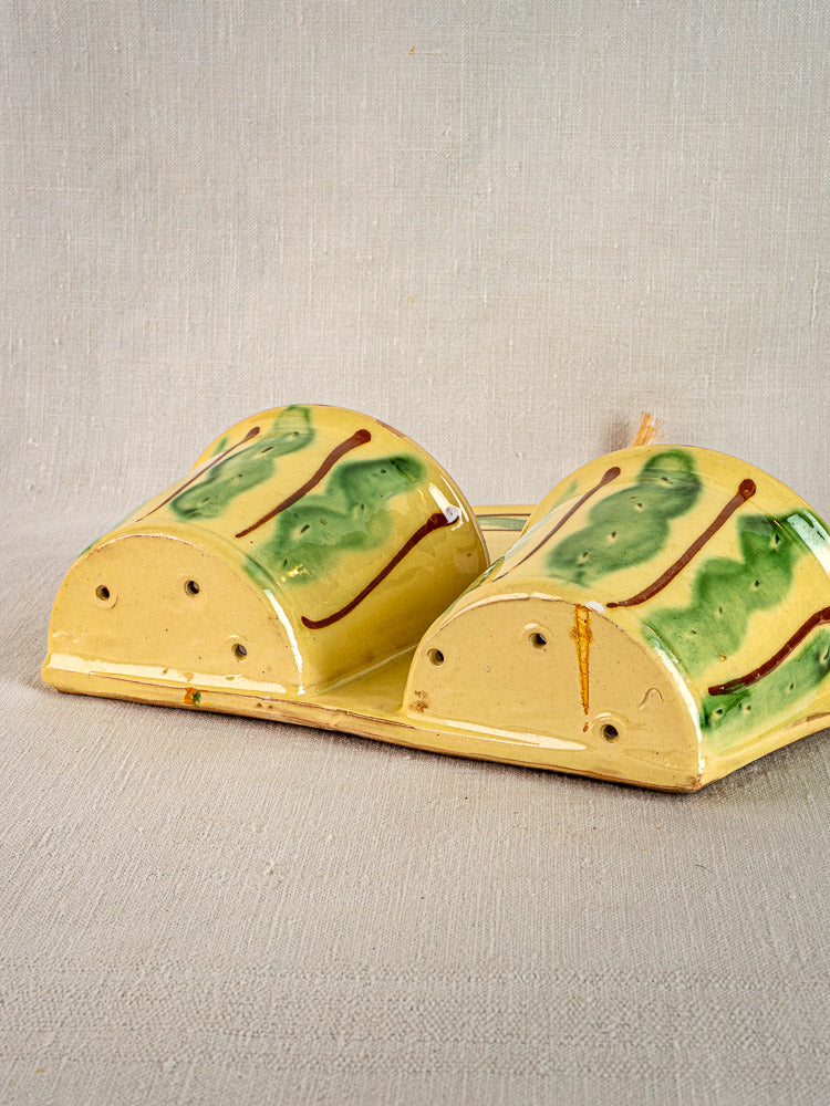 Pair of yellow glazed French earthenware cutlery holders with green-brown designs on beige textured surface.