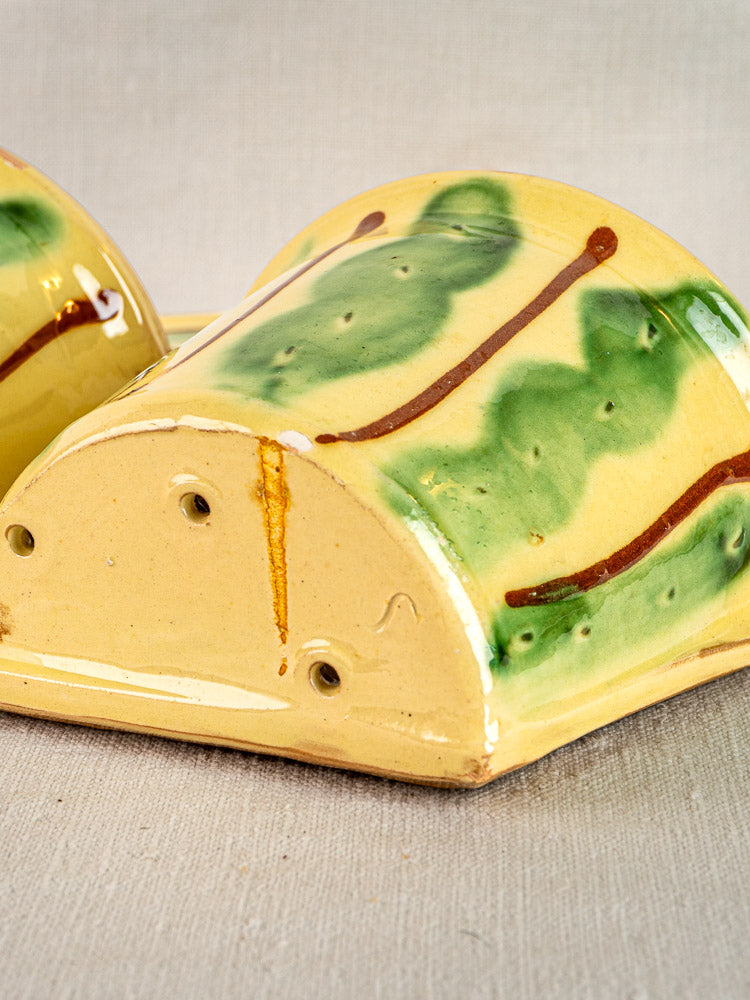 Vintage French Cliousclat cutlery holder with rounded top, yellow base, green and brown glaze accents, displayed on textured beige surface.