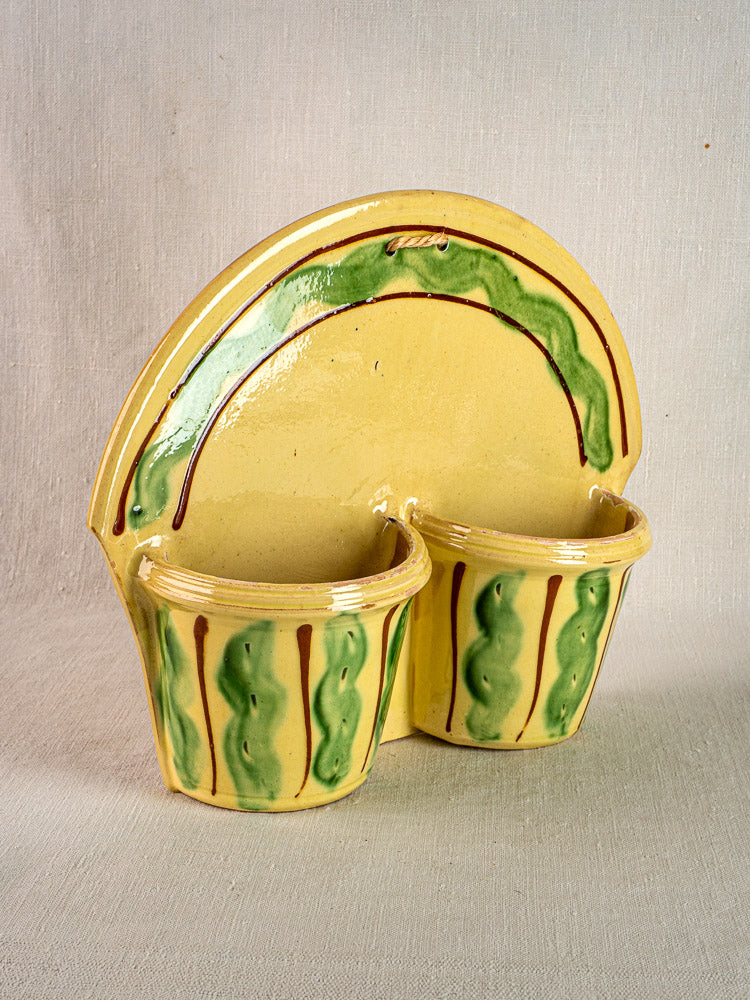 Yellow-glazed French ceramic cutlery holder with green and brown accents, Provençal style, on beige fabric.
