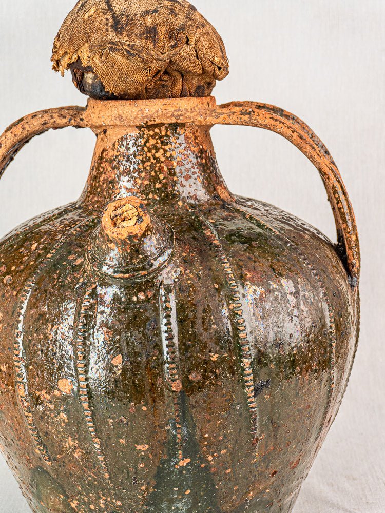 Antique French terracotta cruche with twin handles, spout, mottled brown-green glaze, fabric stopper.