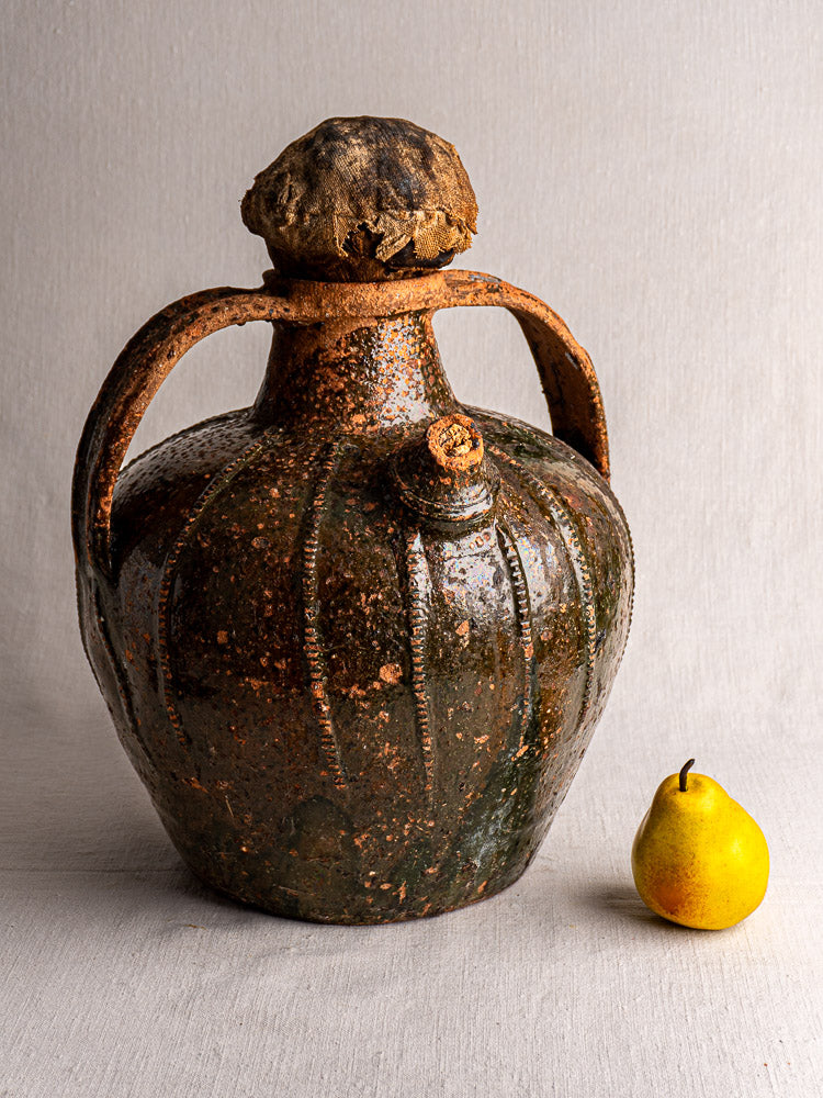 Antique French glazed terracotta oil cruche with bulbous body, dark brown finish, and twin handles.