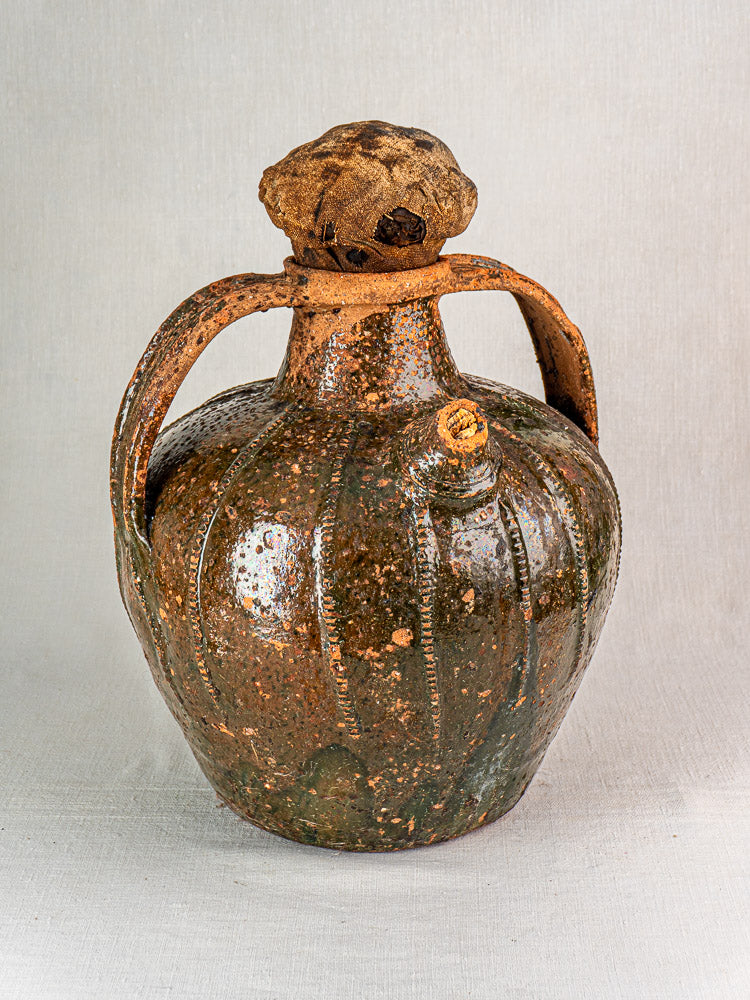 Antique French glazed terracotta oil cruche with bulbous body, dark brown finish, and twin handles.