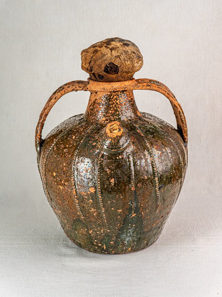 Antique French terracotta oil cruche with two handles, speckled brown and green glaze.