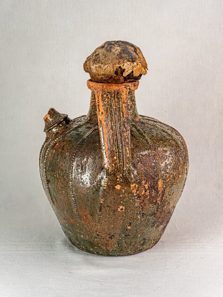 Antique French terracotta cruche with brown glaze, ridged body, side spout, and worn stopper.