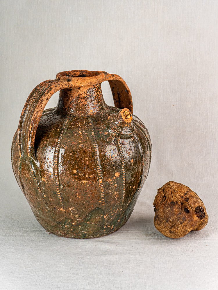 Antique French terracotta walnut oil cruche with speckled brown-green glaze and two handles.
