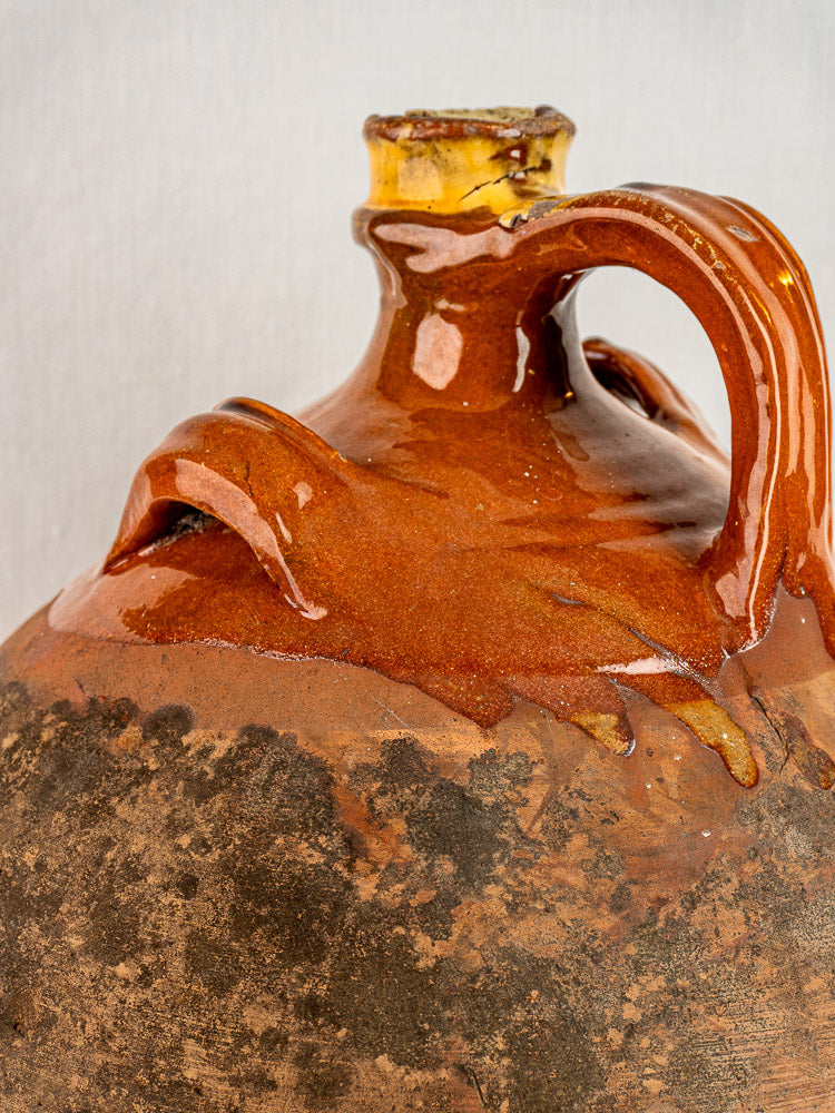 Antique French Auvergne terracotta oil jar with original cork, glazed top, rough textured base.