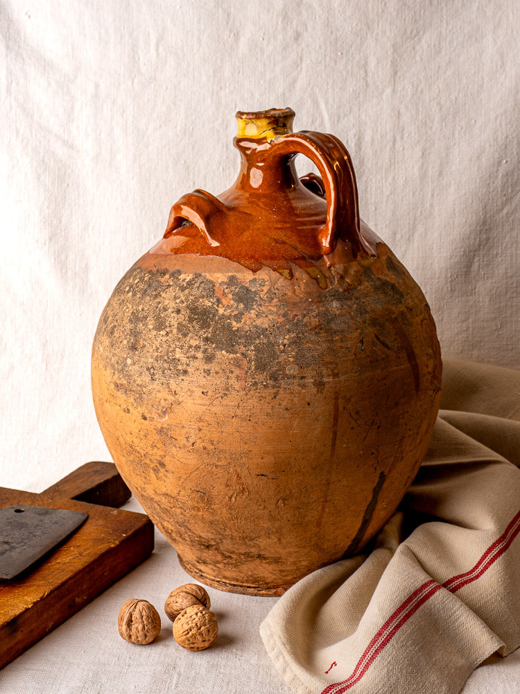 Antique French terracotta oil jar with cork, round form, glazed upper and rustic unglazed base.