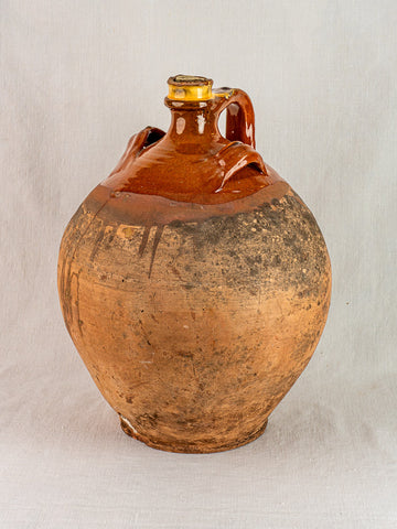 Antique French terracotta oil jar with cork, round form, glazed upper and rustic unglazed base.