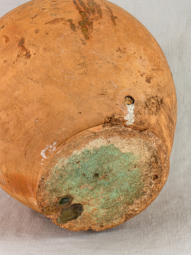 Antique French Auvergne terracotta oil jar with original cork, worn base and textured patina.