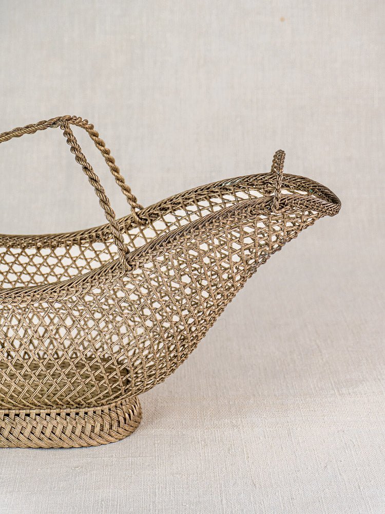 Antique French silver plate wirework wine bottle holder in Belle Époque style on neutral fabric.