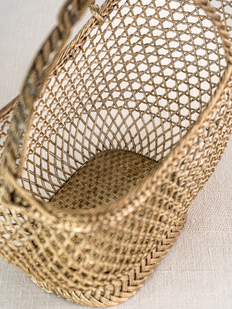 Antique French wine bottle holder with Belle Epoque silver plate wirework on a light textured surface.