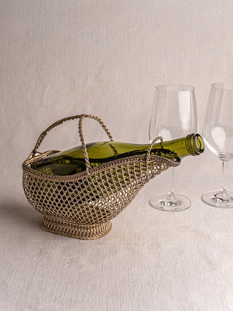 Antique French silver plate wirework wine bottle holder with curved spout and tall handle on light surface.