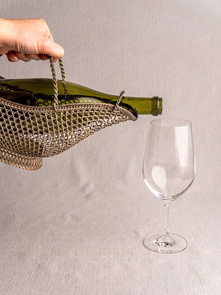 Antique French silver-plated wine bottle holder tilts a green bottle to pour into glass.