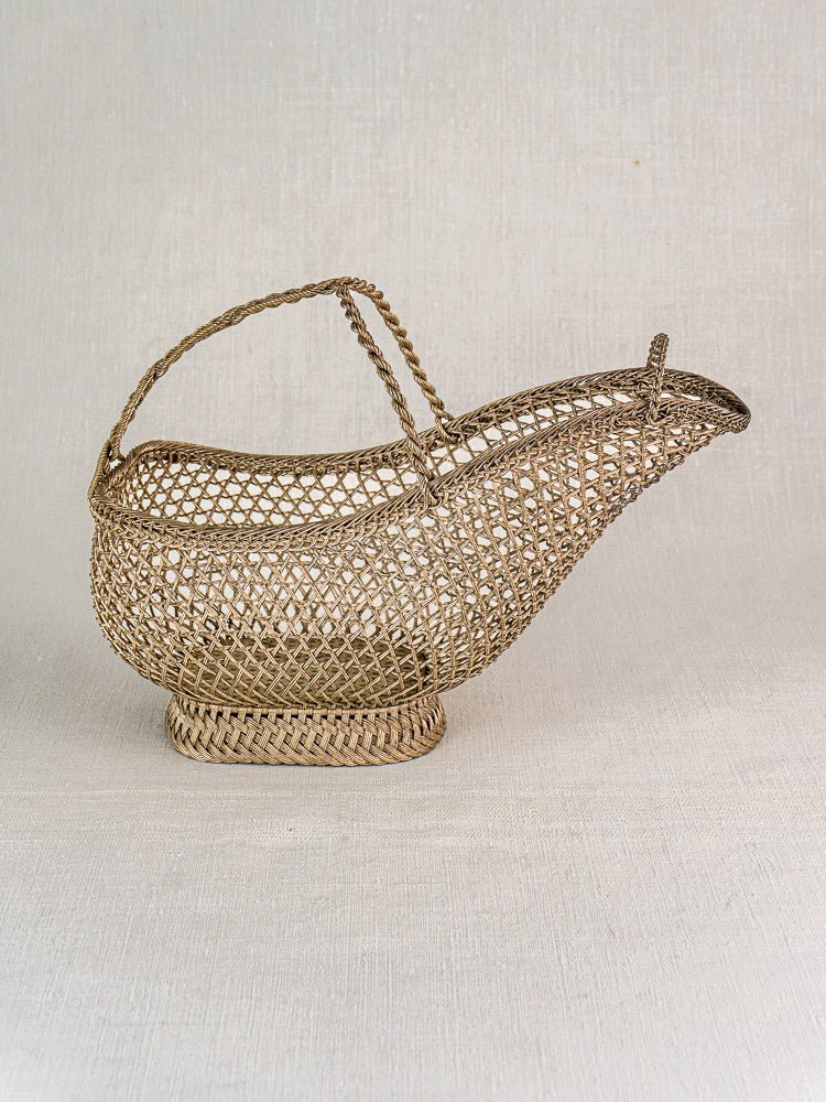 Antique French Belle Époque silver plate wine bottle holder with woven wirework, on neutral fabric.