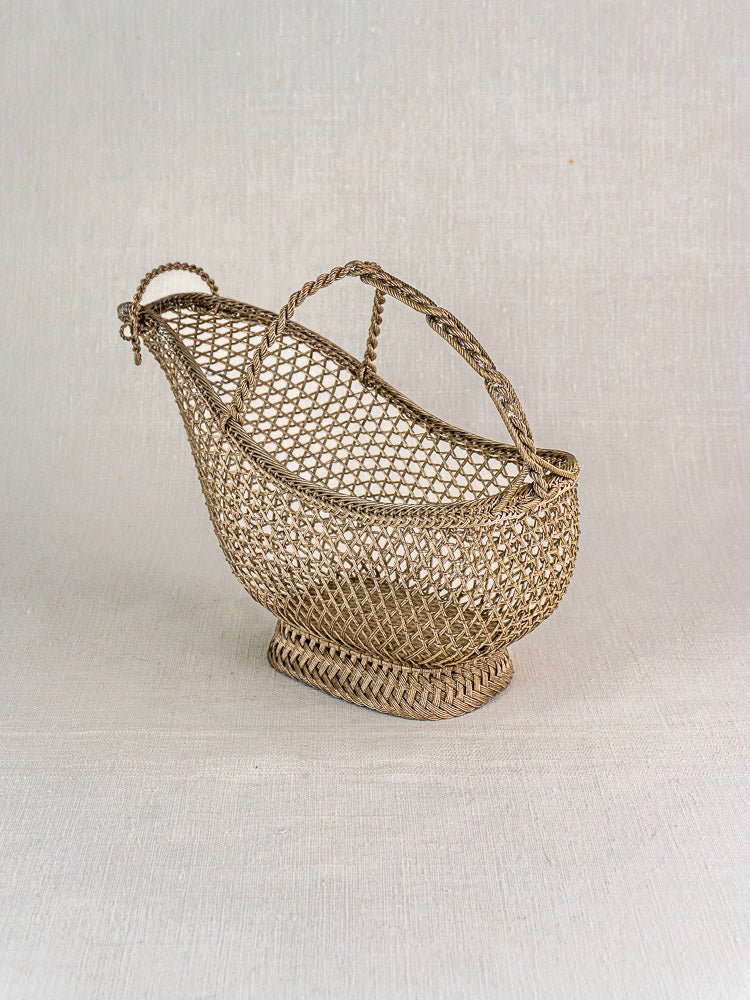 Antique French silver plate wine bottle holder with open mesh basket and twisted handle, on light gray background.