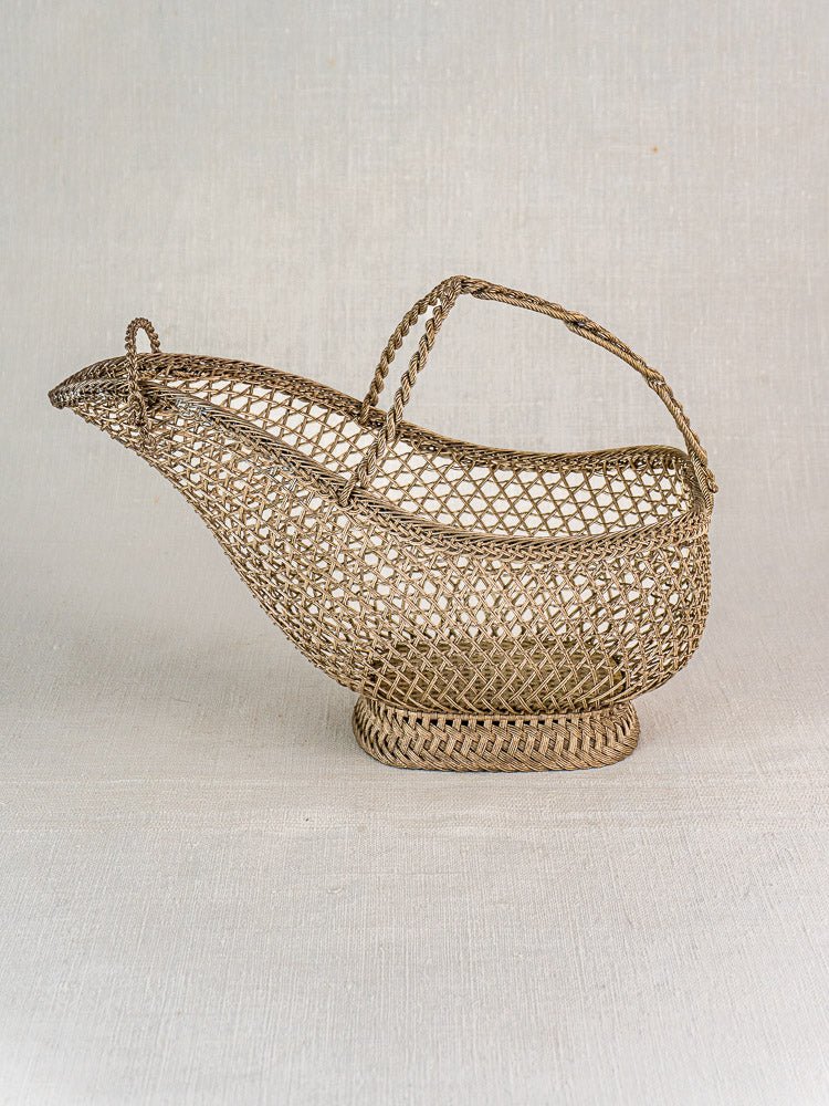 Antique French silver plate wirework wine bottle holder with arched handle, Belle Epoque era, on fabric.