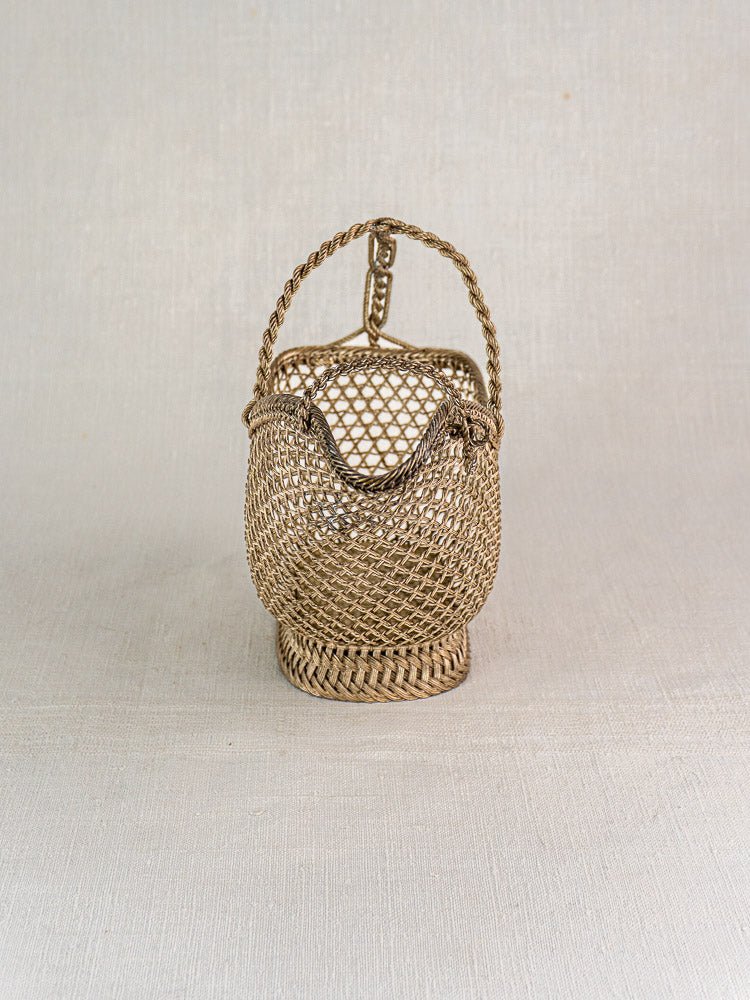 Small round antique French wine bottle holder with intricate silver plate wirework and braided handle.