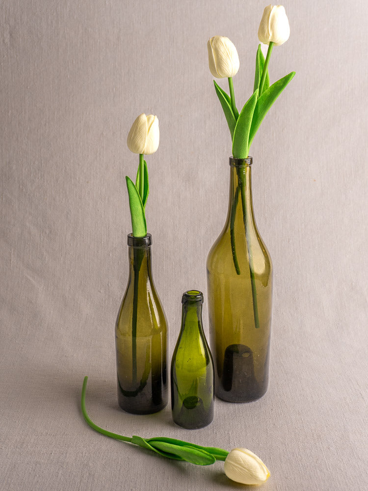 Set of three mid-19th-century French hand blown olive green wine bottles with white tulips.