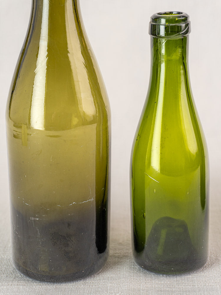Pair of mid-19th century French hand blown wine bottles in olive-green and clear glass.