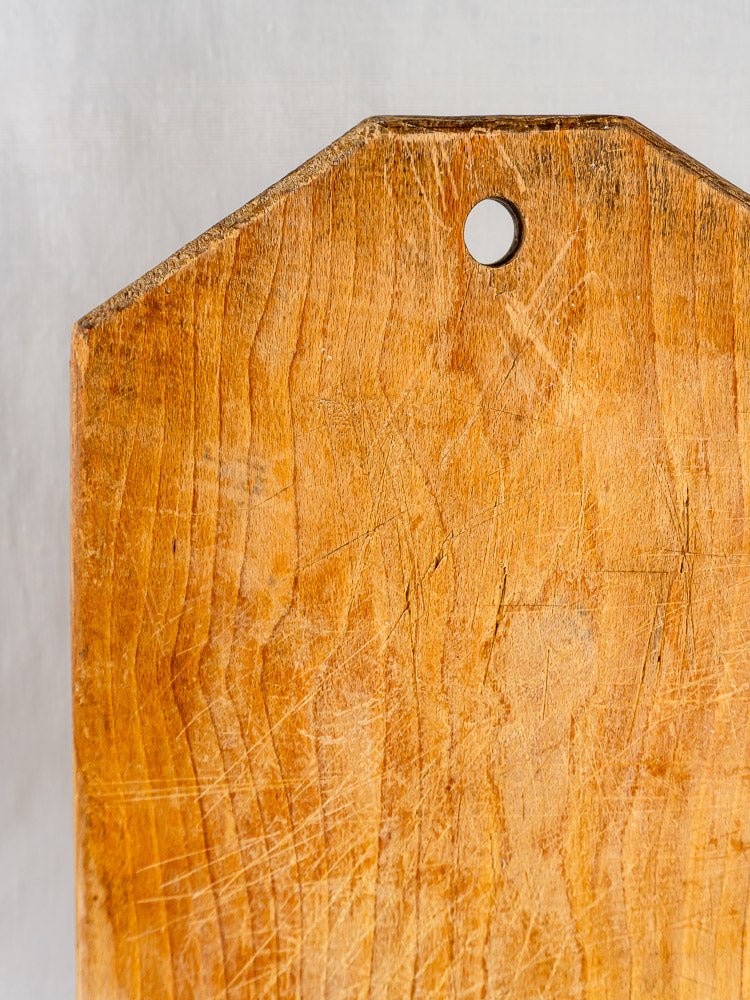 French antique 19th-century wooden tombstone cutting board with visible scratches and hanging hole, on light background.
