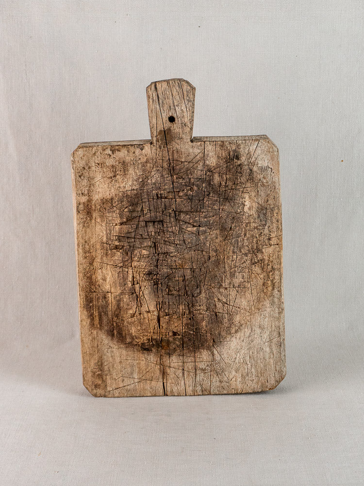 Antique French solid wood bread board with handle, late 19th-century, worn patina and knife marks.