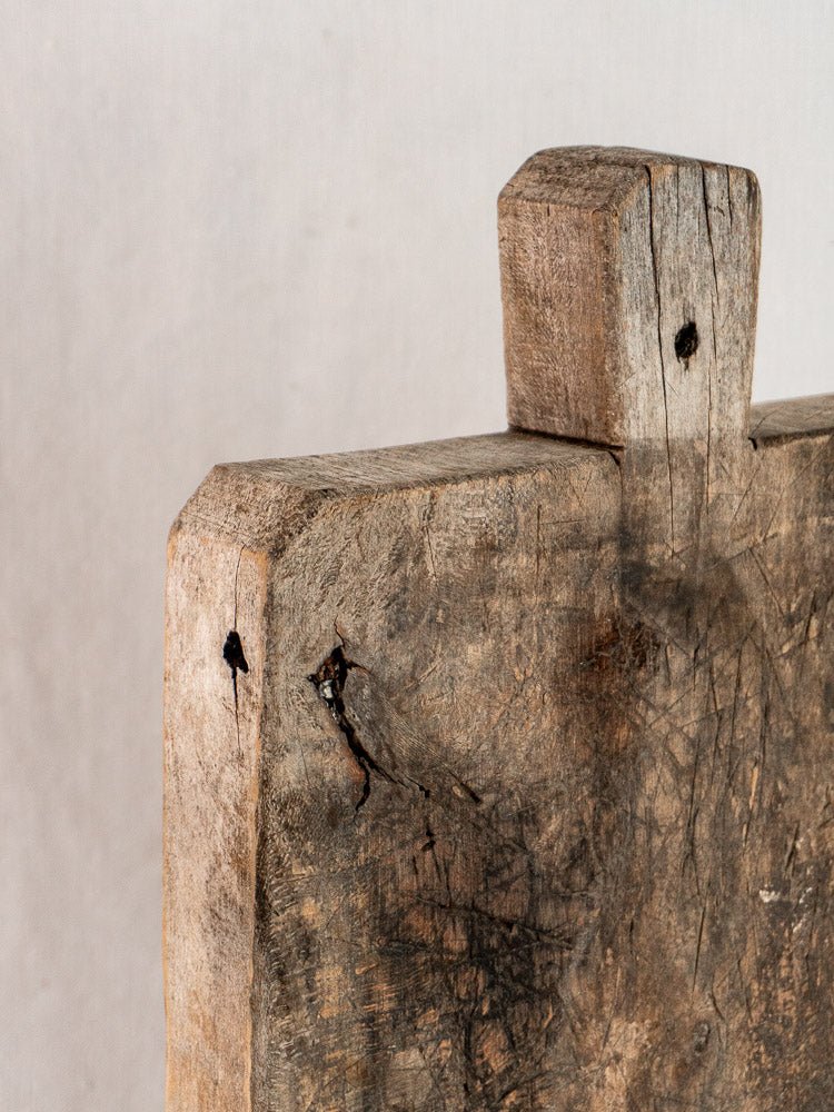 Antique French solid wood bread board with handle, late 19th century, weathered patina, light background.