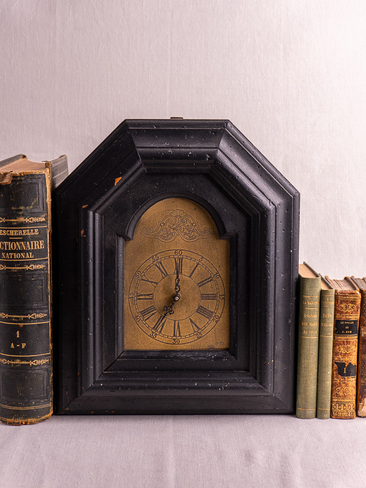 Antique French black wood wall clock with gold face, ornate detail, circa late 19th century.