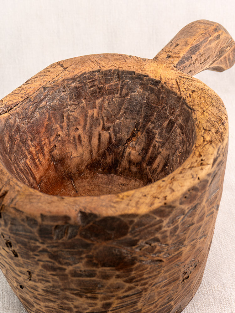Antique French wooden mortar and pestle with hand-carved details and textured interior, rustic design.