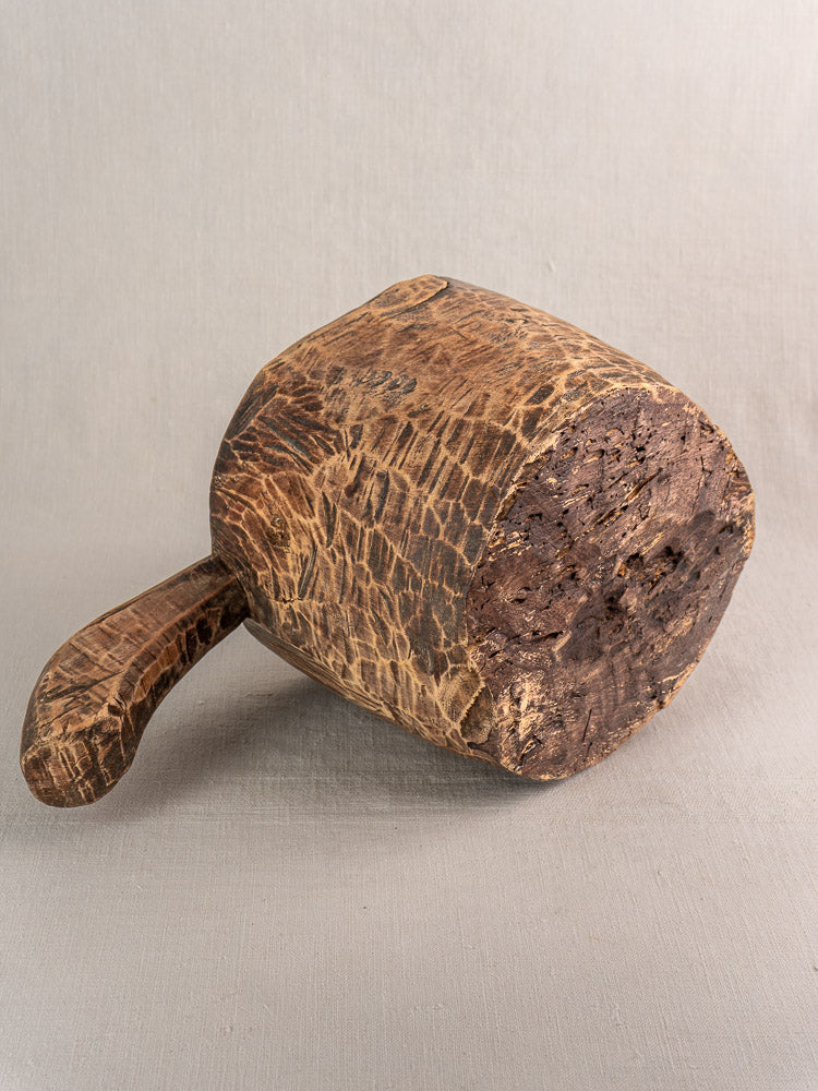 Antique French hand-carved wooden mortar and pestle with textured, weathered surface on light background.