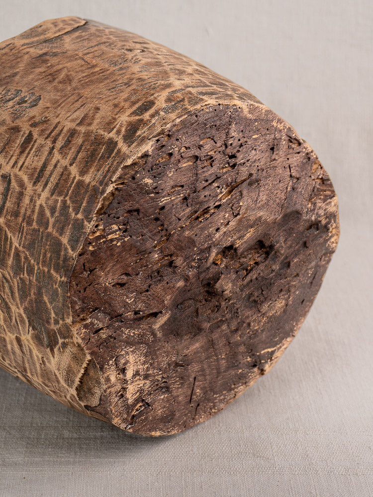 Antique French wooden mortar and pestle with hand-carved detail, weathered patina, on light gray fabric.