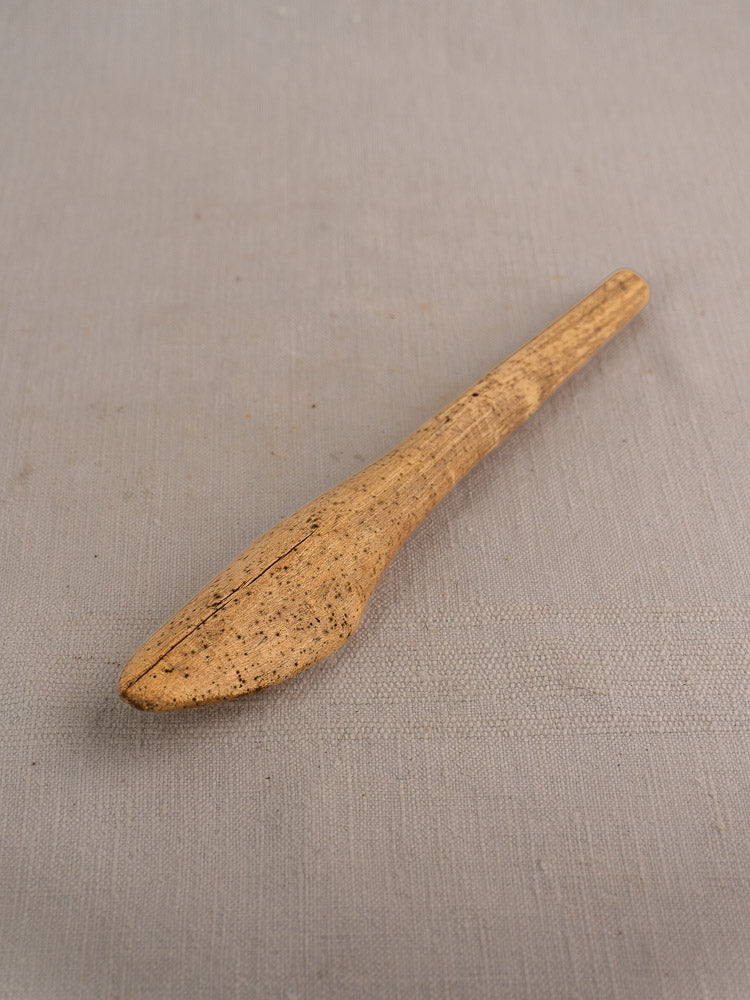 Antique French hand-carved wooden mortar and pestle with rustic farmhouse design on beige textured surface.